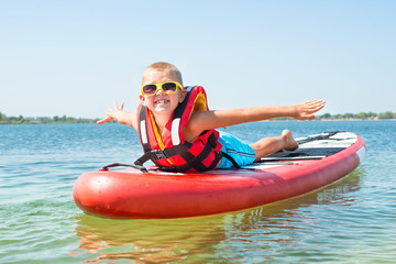 Boy swimming on stand up paddle board.Water sports , active lifestyle.	