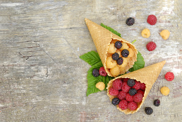 Raspberry red, yellow and black in waffle cups on a gray wooden background.
