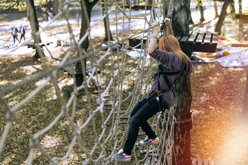 Obraz na płótnie Canvas happy girl, selective focus, climbing gear in an adventure park are engaged in rock climbing rope road, arboretum, insurance, attraction, amusement park, active recreation, autmn