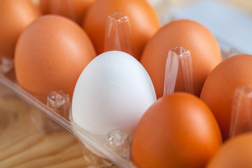 Close-up view of raw chicken eggs in egg box on wooden background
