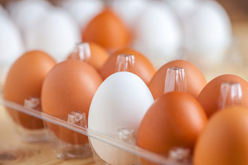Close-up view of raw chicken eggs in egg box on wooden background