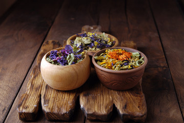 Dry herbs in military uniform on wooden background.
