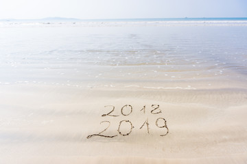 The inscription on the sand 2018 2019 against the background of sea and sky
