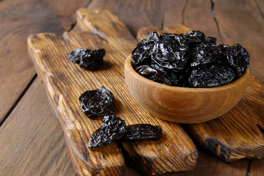 Dry plum in a wooden bowl on the table.