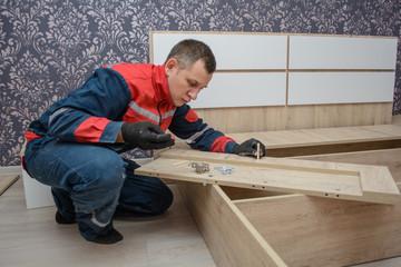 Assembling new wooden bed by hand in room. Man putting together new furniture.