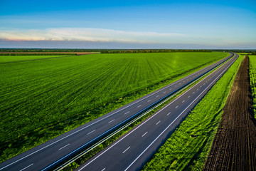 empty asphalt road along the green fields. Road seen from the air. Aerial view landscape. drone...