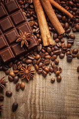 Texture spilling coffee beans, chocolate, cinnamon and cloves. Top view. Copy space.