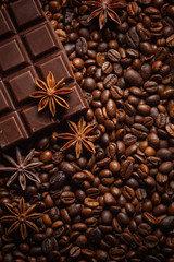 Texture spilling coffee beans, chocolate, cinnamon and cloves. Top view. Copy space.