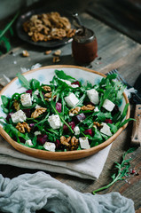 Salad with beets, walnuts, feta cheese and arugula. Rustic style salad on a dark wooden background