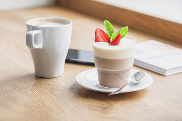 Fototapeta na wymiar Cup of coffee and dessert with strawberry and leaves of mint
