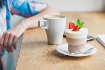 Woman in the cafe with a cup of coffee and strawberry dessert