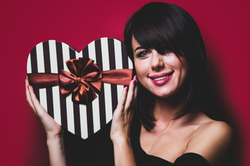 portrait of the beautiful young woman with gift on the vinous background