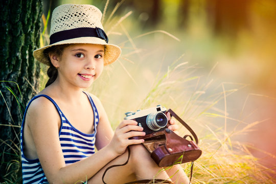 portrait of the beautiful girl with camera sitting near the tree