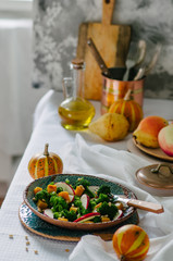 Salad with baked pumpkin, apple, broccoli and pine nuts. Ceramic plates handmade. Rustic style.