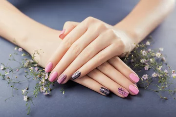  Roze en zwarte manicure met bloemen op een grijze achtergrond. Nagel kunst © maryviolet