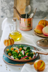 Salad with baked pumpkin, apple, broccoli and pine nuts. Ceramic plates handmade. Rustic style.