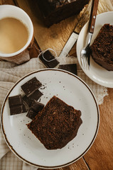 Chocolate pound cake pieces on white plates. Brown toned, wooden background, directly above.