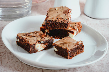 Homemade chocolate brownies with cream cheese filling on white plate. Perfect moist texture inside of brownies.