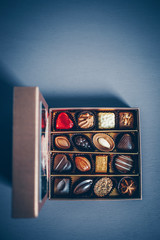 A small box of chocolate pralines and truffles assorted. Blue toned background, directly above.