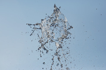 Splashes of flying water from the fountain against the blue sky