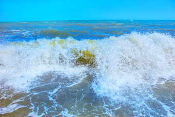 Fototapeta premium Sea waves roll on to shore with foam and sea spray.