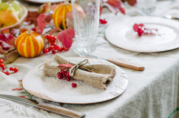 Autumn table setting with beautiful plates, pumpkins and and flowers, fall home decoration for festive dinner.