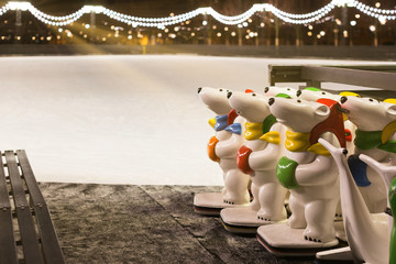 Skater helpers to keeps balance on ice, empty ice rink on background in the evening. Assistant...