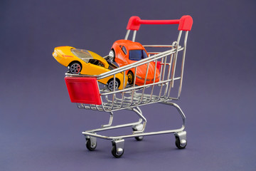 The concept of buying ordinary cars and sports cars. Purchase leasing. Cars in a metal trolley against a background of violet color.