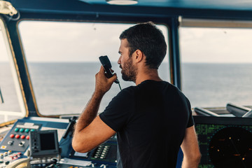 Marine navigational officer is reporting by VHF radio during navigation watch. Bridge GMDSS watch