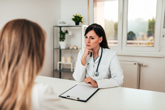 Serious Female Doctor Listening To A Patient.