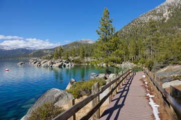 Scenic wooden path leading along the edge of spectacular lake in the mountains.