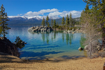 Beautiful view of a sandy beach leading toward the emerald lake by the mountains