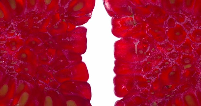 Two Raspberry Halves Give Juice. Raspberries are compressed and crushed close-up on a bright white background, creating a juicy burst of pulp and a bright shell. Shooting at 120fps