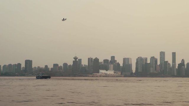 Sea plane flying over cloudy Vancouver skyline