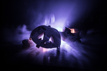 Horror Halloween concept. Close up view of scary dead Halloween pumpkin glowing at dark background.