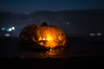 Horror Halloween concept. Close up view of scary dead Halloween pumpkin glowing at dark background.
