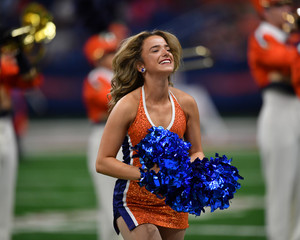 Young college cheerleader performing at a college football game