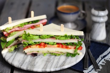 Fresh tasty sandwich with lettuce, ham, cheese, avocado, and tomato. English breakfast