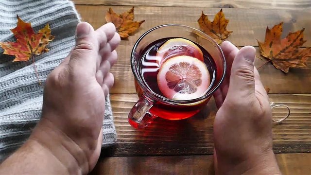 Mans' hand holds a glass cup of tea slow motion