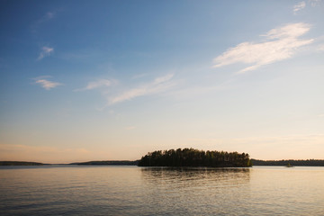 Obraz premium Lonely island on the lake on the horizon at sunset