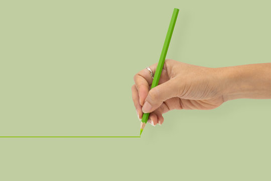 Hand with color pencil is writing line isolated on green background