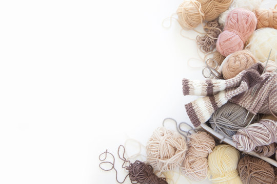 Neutral beige yarn for knitting is in the basket. Woolen warm socks. White background.