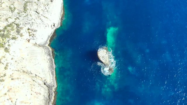 Drone shot over rocks and Cliffs with wave hitting a small rock in the Mediterranean sea of Malta 3