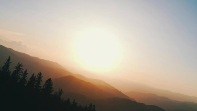 Pov mode rotate a slow motion panorama of the peaks of beautiful mountains covered with trees, mountain lake at sunset on sunny day in summer. Ray of sunshine. Lens flare. Solar reflection. Lens flare
