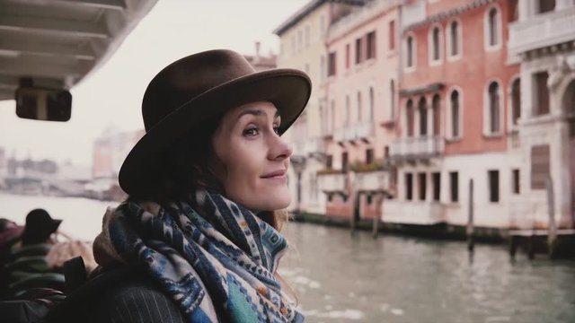 Beautiful excited Caucasian tourist girl smiling, enjoying amazing atmospheric gondola excursion tour in autumn Venice.