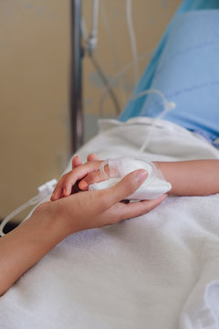 Mother holding child's hand who fever patients in hospital to give encouragement