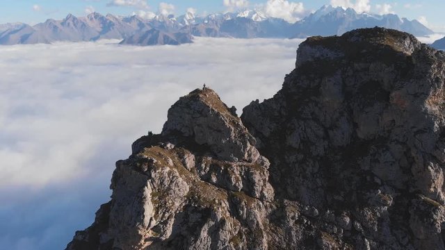 Aerial shot of climbers on top of a mountain high above the clouds.