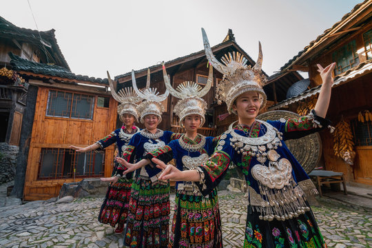 China, Guizhou, Miao women wearing traditional dresses and headdresses posing on village square