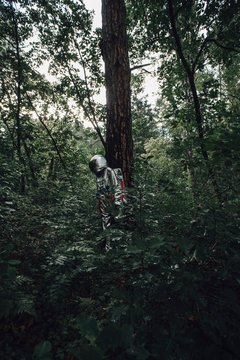 Spaceman exploring nature, looking at plants in forest