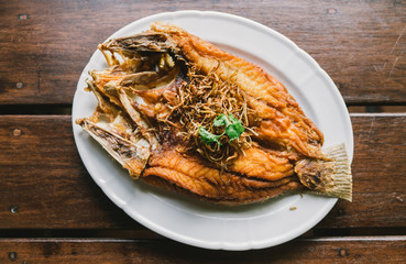 Delicious Asian - Asia eating Thai food. Fried fish on plate with vegetables. in a plate and wooden table background.